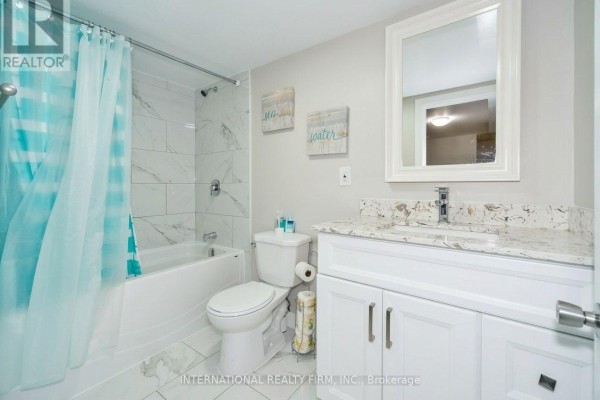 Basement bathroom with a white bathtub, toilet, vanity with a granite countertop, and light grey walls. - Bsmtapt - 328 Sheppard Avenue, Pickering