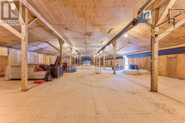 Interior view of a large open commercial space with wooden beams and plywood walls. - Building #2 Upper #1 - 434 Lynden Road, Brantford