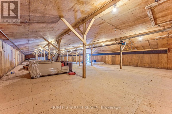 Wide shot of the spacious interior commercial area with exposed wooden beams and overhead lighting. - Building #2 Upper #1 - 434 Lynden Road, Brantford