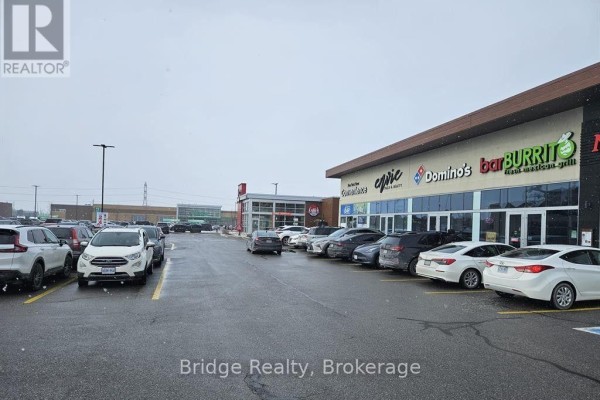 Paved parking lot with cars parked in front of a commercial building with multiple businesses. - Building 4 - 1782 Stonechurch Road E, Hamilton