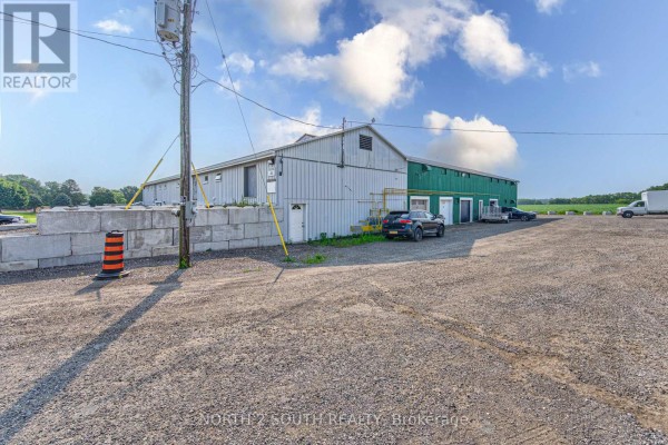 Side view of a commercial building with loading docks and a gravel lot. - Building #4 Upper #1 - 428 Lynden Road, Brantford