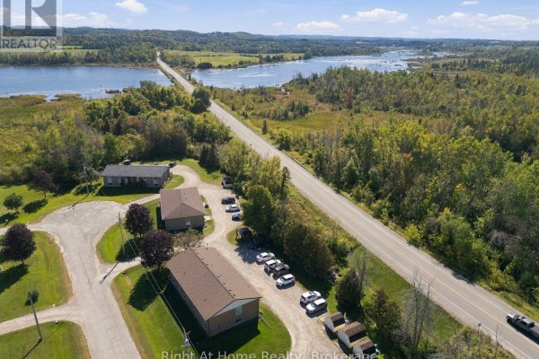 Aerial view showing apartment buildings near a highway and a bridge crossing a body of water. - C - 103 Rita Crescent, Kawartha Lakes