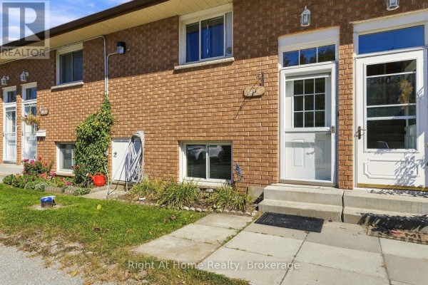 Close-up exterior view of brick apartment building entrances with concrete steps and landscaping. - C - 103 Rita Crescent, Kawartha Lakes