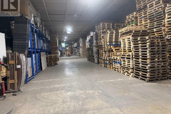 Warehouse aisle lined with wooden pallets stacked high on the right. - C - 111 Snidercroft Road, Vaughan