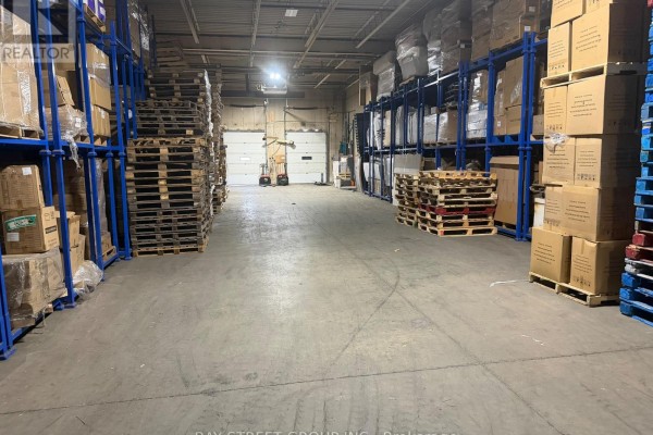 Warehouse interior with shelving units stacked with boxes and pallets on both sides. - C - 111 Snidercroft Road, Vaughan