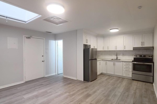 Interior shot of a white kitchen with grey wood-look flooring. - C - 201 Augusta Avenue, Toronto