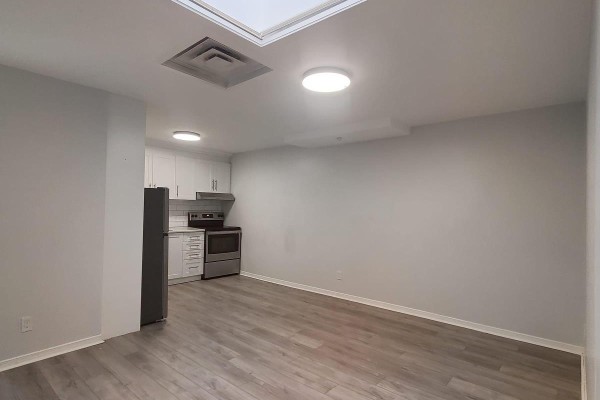 View of a white galley kitchen with grey flooring and a window. - C - 201 Augusta Avenue, Toronto