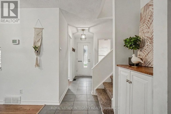 Entrance hallway with tiled floor, white walls and carpeted stairs. - C - 33 Woodfield Drive, Ottawa