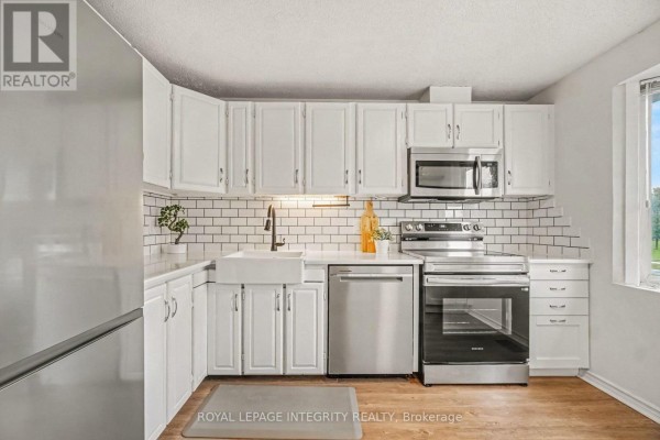 Kitchen with white cabinets, subway tile backsplash, and stainless steel appliances. - C - 33 Woodfield Drive, Ottawa