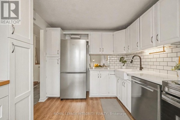 Kitchen with white cabinets, subway tile backsplash, stainless steel refrigerator and sink. - C - 33 Woodfield Drive, Ottawa