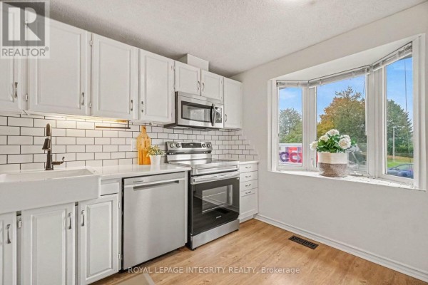 Kitchen with white cabinets, subway tile backsplash, and a bay window view. - C - 33 Woodfield Drive, Ottawa