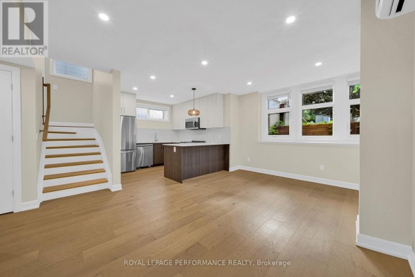Open concept living area with kitchen, island, stairs, and wood floors. - C - 413 Tweedsmuir Avenue, Ottawa