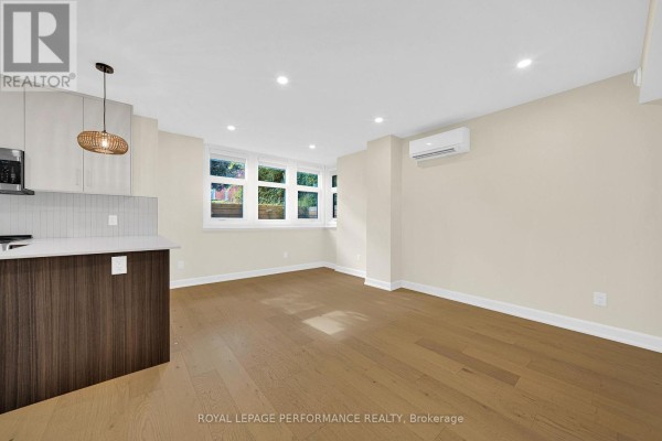 Living space with kitchen island, light walls, and windows overlooking greenery. - C - 413 Tweedsmuir Avenue, Ottawa