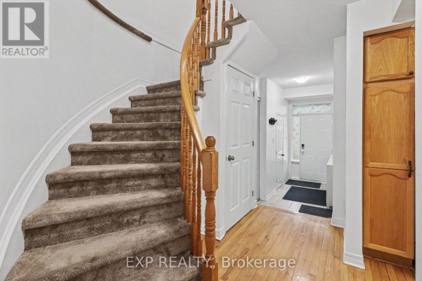Interior staircase with beige carpeted steps and a curved wooden banister, leading upwards. - C - 46 San Remo Private, Ottawa