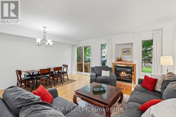 Living and dining room with a gas fireplace, a dining table with chairs, and a sliding glass door to the backyard. - C - 46 San Remo Private, Ottawa