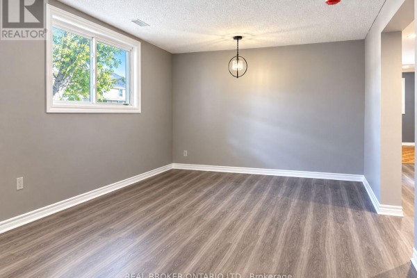 Empty room with grey walls, grey wood-look flooring, and a large window. - C - 93 Brybeck Crescent, Kitchener