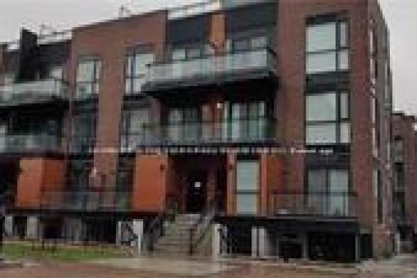 Close-up of a modern brick townhouse with large windows and balconies. - C-302 - 5299 Highway 7 Street, Vaughan