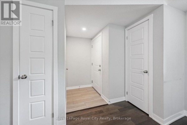Interior hallway with white doors, light wood flooring, and light grey walls. - C1 - 190 Century Hill Drive, Kitchener