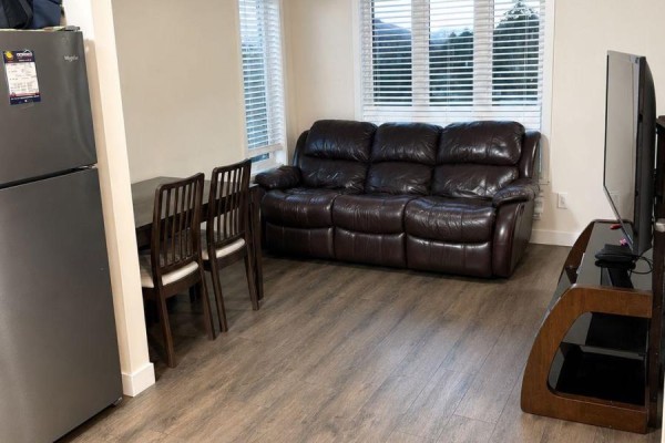 Living space with a leather sofa, television on a media stand, and a closed white door. - C14 - 160 Rochefort Street, Kitchener