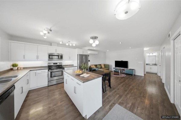 Open-concept kitchen and living area with white cabinets and stainless steel appliances. - C14 1106 Dawson Road, Lorette