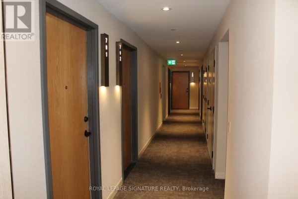 Interior apartment building hallway with wood doors and modern lighting. - C701 - 8 Beverley Glen Boulevard, Vaughan