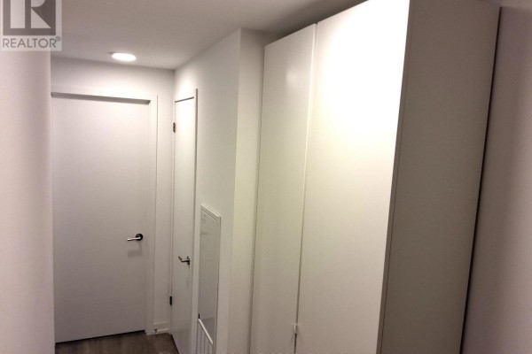 Hallway inside an apartment with white walls and tall closet doors. - C701 - 8 Beverley Glen Boulevard, Vaughan