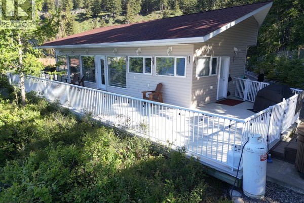 Garage with a covered boat on a trailer, storage shelves, and a garage door. - Cabin 1 155 Birch Bay Resort Road, Fraser Lake