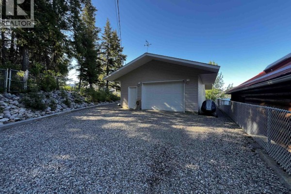 Bedroom with a queen-size bed, wooden dresser, and a window with blinds. - Cabin 1 155 Birch Bay Resort Road, Fraser Lake