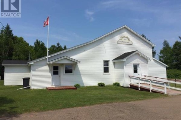A long, white clapboard building with a red and white flag flying in front. - Cambridge Road, Sturgeon