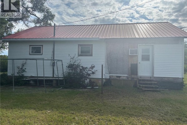 Side view of the house showing white siding, red roof, and a metal swing set in the yard. - Cantuar Acreage, Swift Current Rm No  137
