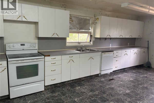 Kitchen with white cabinets, white appliances including a stove and dishwasher, and gray counters. - Cantuar Acreage, Swift Current Rm No  137