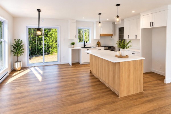 Bright open-concept kitchen with white cabinets, wood island, and garden doors. - Ch. Célestin-pominville, L Ange Gardien