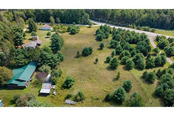 Aerial view of a property with a large cleared lot, several buildings, and surrounding trees. - Ch. Mcneill Lake, Clarendon