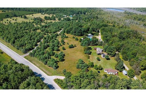 Aerial view of a rural property with houses, a large lot, and dense surrounding forest. - Ch. Mcneill Lake, Clarendon