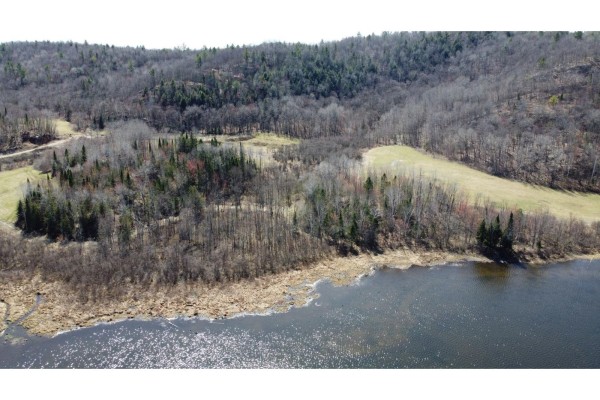 Aerial view of a lake shore with vegetation, adjacent to forest and a cleared area with a road. - Ch. Thomas N., Notre Dame De La Salette