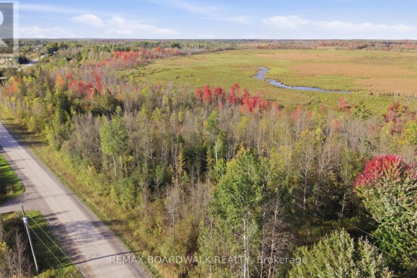 Expansive aerial view of a rural landscape featuring a wooded lot, wetlands, and a paved road. - Con 7 Lot 6 Land O'nod Road, Merrickville Wolford