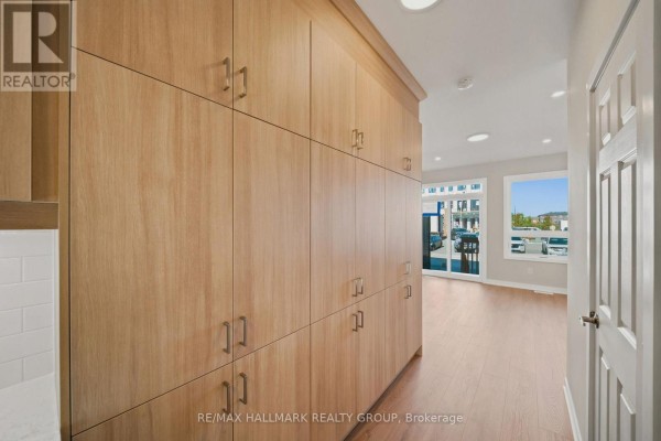 Kitchen area with extensive light wood built-in cabinetry and a hallway leading to a living area. - D - 142 Conservancy Drive, Ottawa