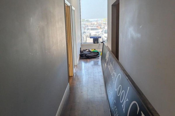 Narrow hallway with gray walls, wooden floor, and a large window overlooking a parking lot. - D - 1472 Dundas Street, London East