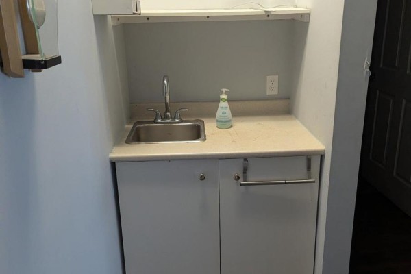Small kitchenette area with a stainless steel sink, beige countertop, and white cabinetry. - D - 1472 Dundas Street, London East