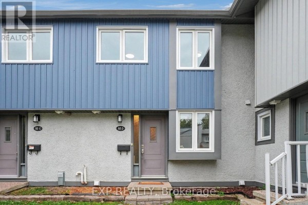 Front view of a townhouse with blue and grey facade and multiple windows. - D - 32 Benlea Drive, Ottawa