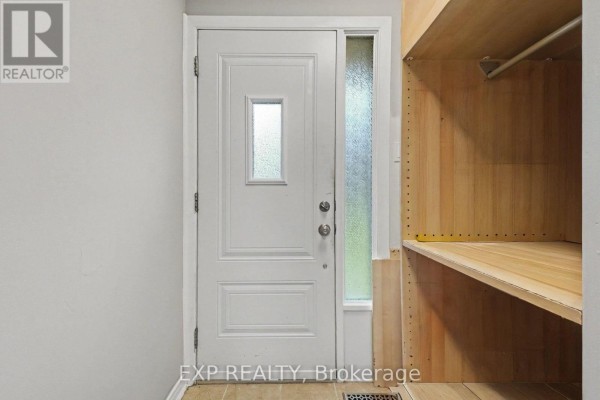 Interior view of townhouse entryway with a white door and wooden shelving unit. - D - 32 Benlea Drive, Ottawa