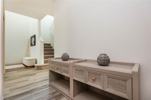 Interior townhouse entryway with white walls, a bench, artwork, and console table. - D 306 Fairhaven Road, Winnipeg