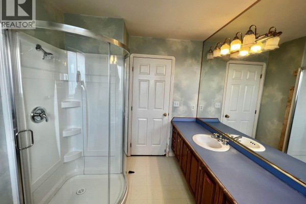 Bathroom with double vanity, dual sinks, mirrored wall, and glass shower. - D 4864 Watling Street, Burnaby