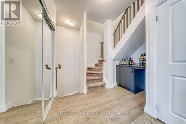Entrance hallway with mirrored closet, carpeted stairs, and a wet bar. - D-803 - 5289 Highway 7, Vaughan