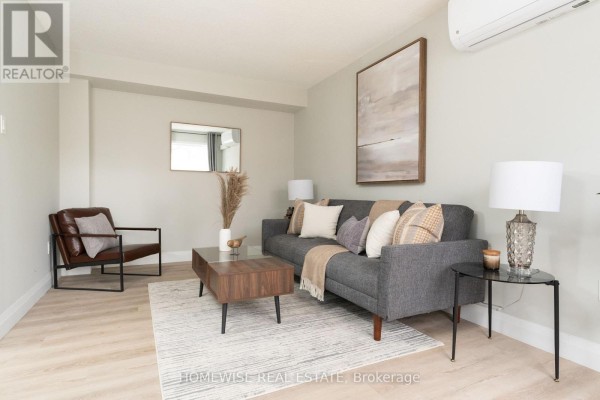 Living room with a dark leather chair, grey sofa, coffee table, and a mirror. - D1 - 240 Ormond Drive, Oshawa