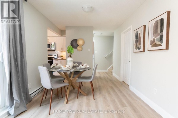 Dining area with glass table, grey chairs, and a hallway with stairs visible. - D1 - 240 Ormond Drive, Oshawa