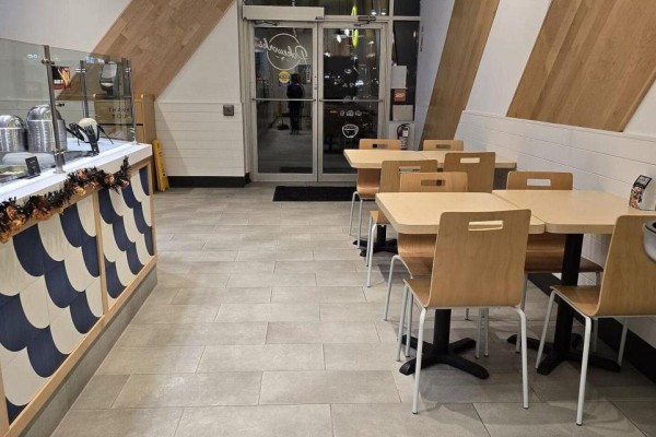 Seating area in PokeWorks restaurant with tables, chairs, and entrance doors. - D1-b - 2465 Appleby Line, Burlington