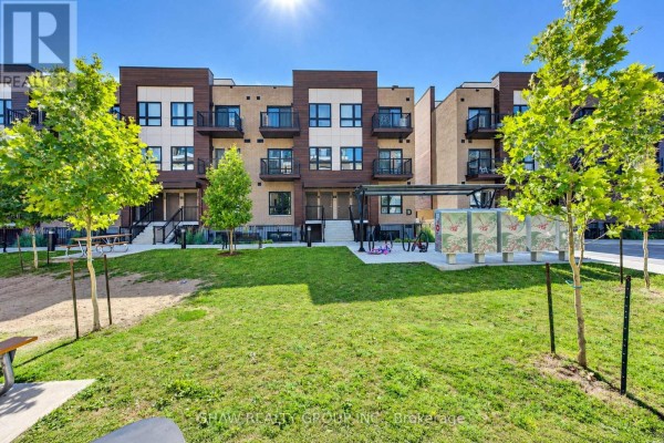 Green lawn and trees in front of apartment building entrance with benches and picnic tables. - D16 - 10 Palace Street, Kitchener
