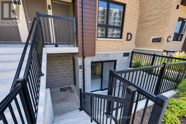 Exterior view of townhouse entrances with concrete steps, black metal railings, and brick facade. - D16 - 10 Palace Street, Kitchener