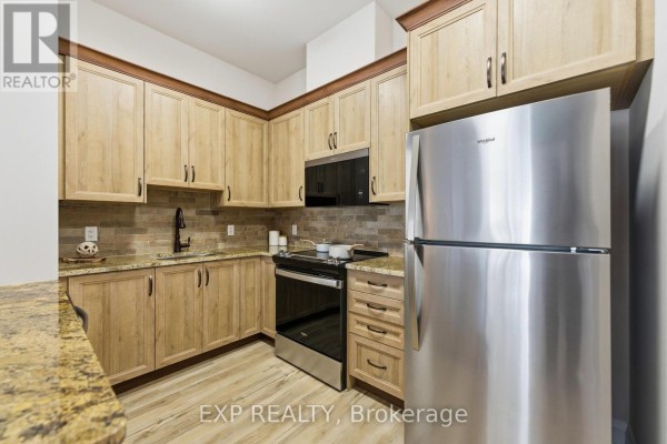 Close-up of kitchen with granite countertops, stove, and refrigerator - D304 - 277 Coleman Street, Carleton Place